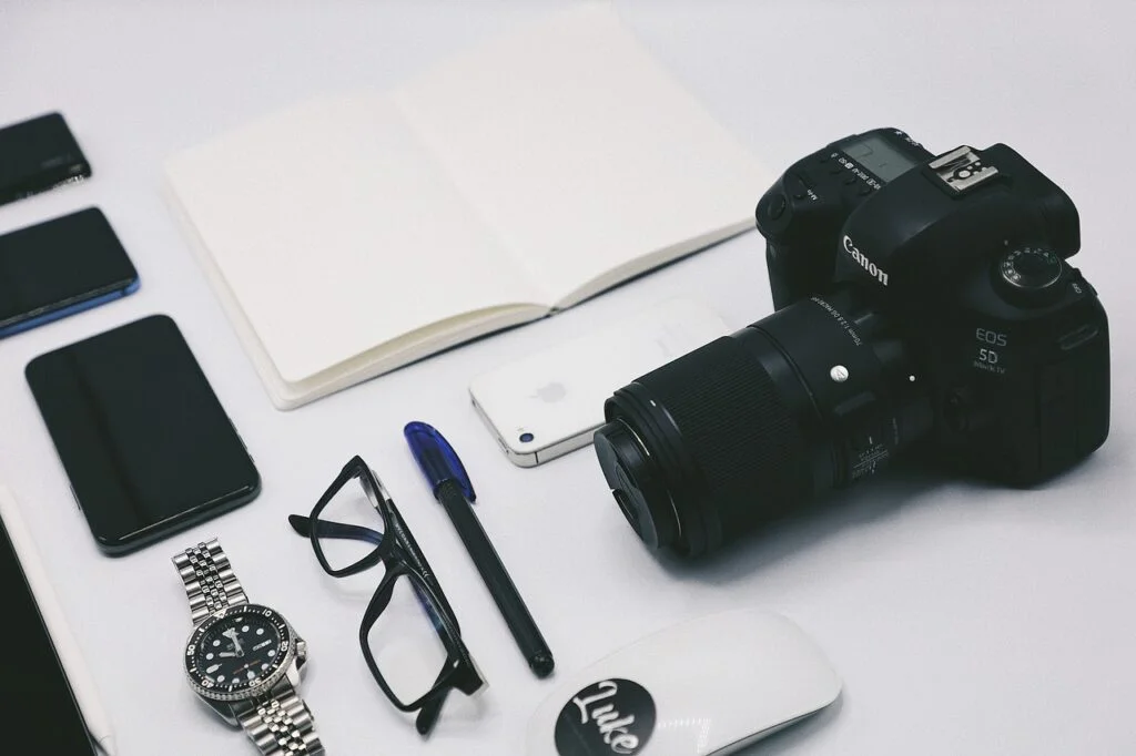 Camera, pen, and other office supplies on a table for product photography setup